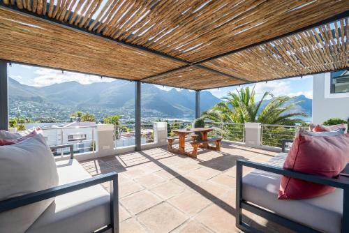 a patio with two chairs and a table and mountains at Hout & About Guest House in Hout Bay