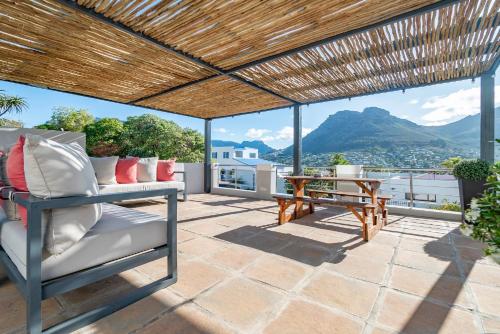 a patio with a table and chairs and a view at Hout & About Guest House in Hout Bay