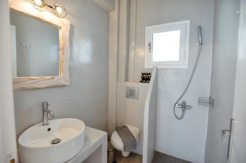 a white bathroom with a sink and a shower at Aspro Phos Santorini Hotel in Perissa