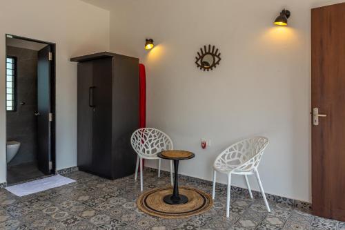 two chairs and a table in a room at SaffronStays Apricus Farm, Karjat in Karjat