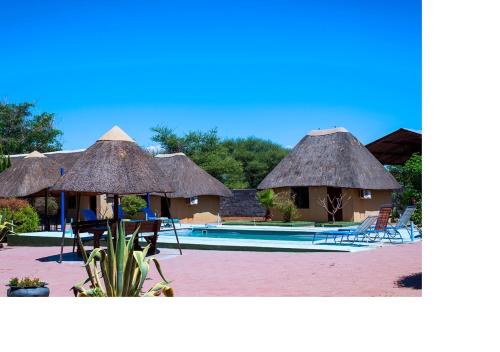 un complejo con piscina y algunas sillas y sombrillas en MSC Hotel Otjiwarongo en Otjiwarongo