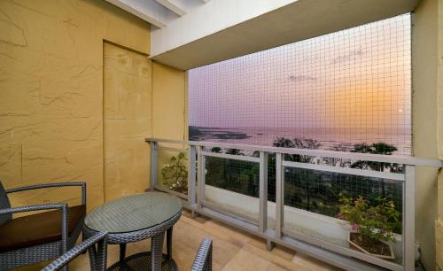 a balcony with a table and chairs and a large window at The Resort in Mumbai