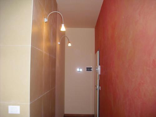 uma casa de banho com um chuveiro e uma parede vermelha em Scendi dal treno em Bolonha