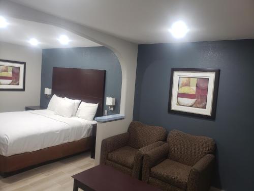 Habitación de hotel con cama y silla en Cotulla Executive Inn en Cotulla