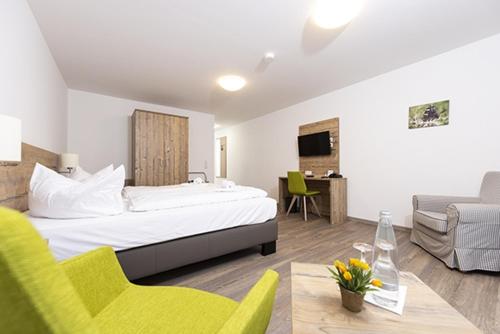 um quarto de hotel com uma cama, um sofá e uma mesa em Hotel garni Milseburg em Hilders