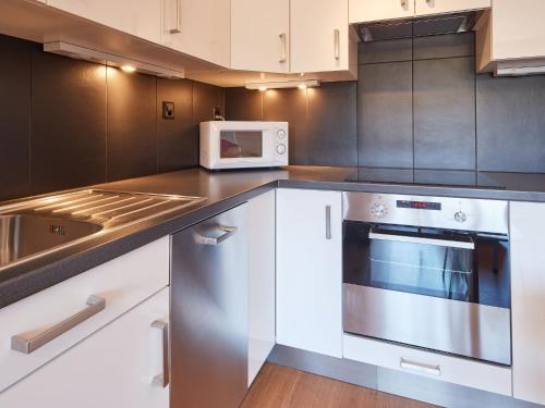 a kitchen with white cabinets and a microwave at Apartment Mirabeau by Interhome in Les Collons