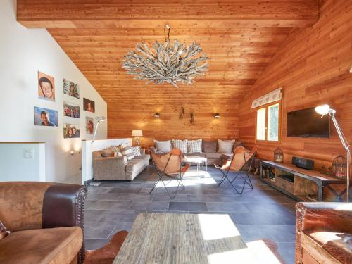 a living room with a wooden ceiling with a chandelier at Chalet Hiboux by Interhome in Les Collons