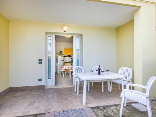 un patio con una mesa blanca y sillas en Apartment Robinia-Pinetine-4 by Interhome, en Duna Verde