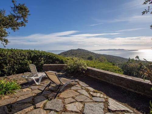 une paire de chaises assises sur une terrasse en pierre donnant sur l'eau dans l'établissement Holiday Home Village Les Fourches by Interhome, à Cabasson