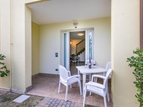 un patio con una mesa blanca y sillas en Apartment Robinia-Pinetine-2 by Interhome, en Duna Verde
