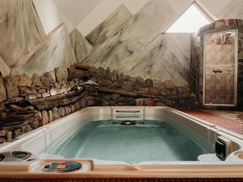 a jacuzzi tub with a stone wall at Bacówka Biały Jeleń in Iwkowa
