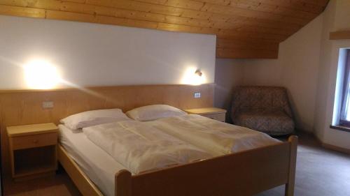 a bedroom with a large bed and a chair at Hotel Casa Alpina - Alpin Haus in Selva di Val Gardena