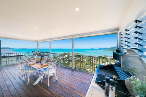 Airlie Beach的住宿－South Hamptons Beach House，阳台配有桌子,享有海景。