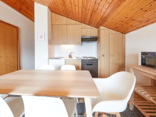 a kitchen with a wooden table and white chairs at Apartment Le Hameau-7 by Interhome in Les Collons