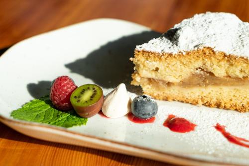 a piece of cake with powdered sugar on a plate with fruit at Bacówka Biały Jeleń in Iwkowa