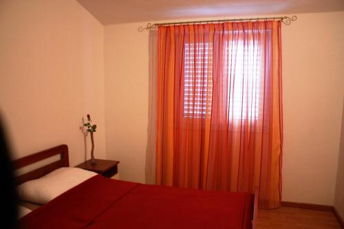 een slaapkamer met een bed en een oranje gordijn bij Apartments Jelena in Trogir