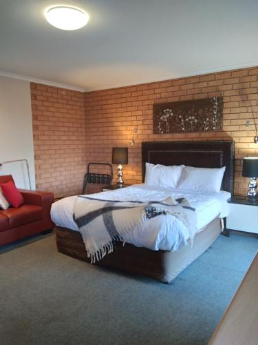 um quarto com uma cama grande e uma parede de tijolos em Bristol Hill Motor Inn em Maryborough