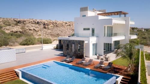 a villa with a swimming pool in front of a house at Sea Pearl Beachfront Villas - Breeze in Ayia Napa