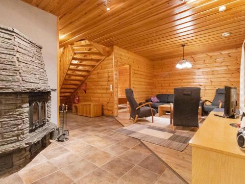 a living room with a fireplace in a log house at Holiday Home Kivikko by Interhome in Laitikkala