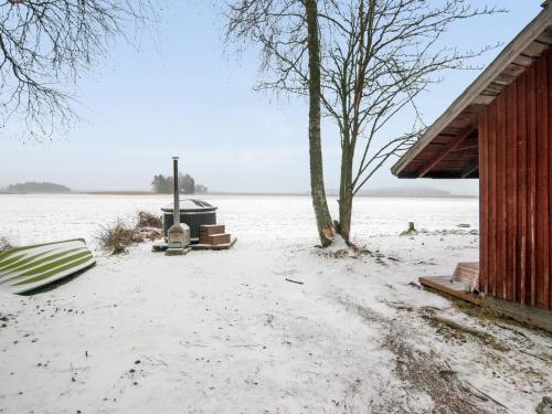 a snow covered yard next to a building and a tree at Holiday Home Rannantupa by Interhome in Hersala