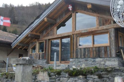 a wooden house with glass windows and a flag at Chalet La Plagne jacuzzi vue top in Montchavin