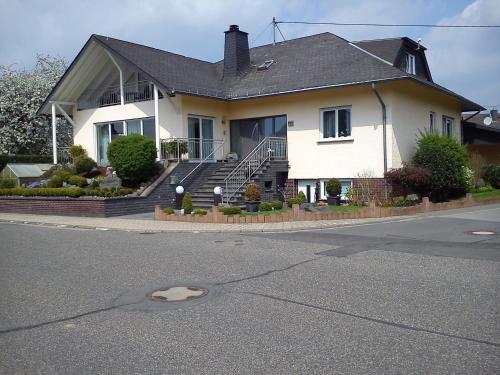 a large white house with stairs and a porch at Ferienwohnung Schmitz in Anschau