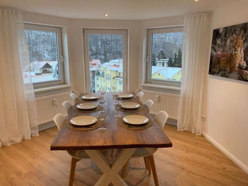 a dining room with a table with chairs and windows at Ferienwohnung Luxusblick in Bad Harzburg