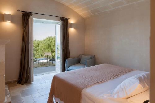 a bedroom with a bed and a chair and a window at Villa Margareta in Ostuni
