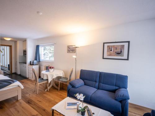 Apartment Chesa Corvatsch 111 - Champfer by Interhome في سورليج: غرفة معيشة مع أريكة زرقاء وطاولة