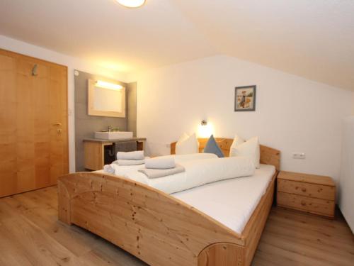 a bedroom with a large wooden bed with white pillows at Holiday Home Sonnblick by Interhome in Uderns