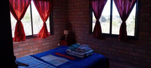 a bedroom with a bed with a blue blanket and windows at Cabaña Casablanca in La Granja