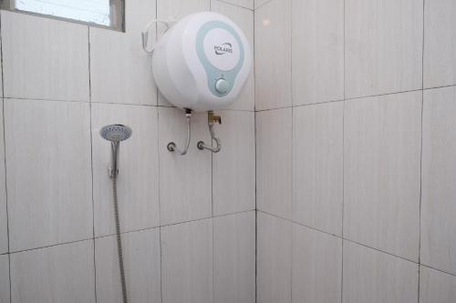 una ducha con cabezal de ducha en una pared de azulejos en Urbanview Syariah Zidney 3 Salatiga by RedDoorz, en Salatiga