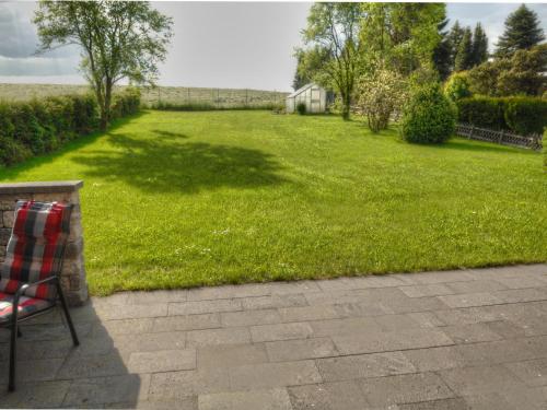 a chair sitting on a patio with a grass yard at Apartment Belvedere by Interhome in Manderscheid