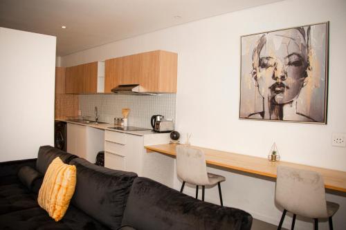 a living room with a couch and a kitchen at Urban Oasis Apartments at Freedom Plaza in Windhoek