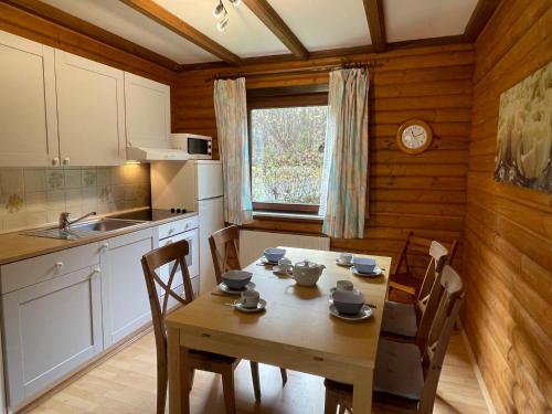 eine Küche mit einem Holztisch sowie einem Tisch und Stühlen in der Unterkunft Apartment Ferienpark Himmelberg-2 by Interhome in Thalfang
