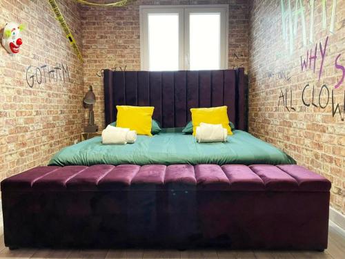 uma cama roxa com almofadas amarelas num quarto em NEW - Bat'Appart - DIJON - Insolite em Longvic