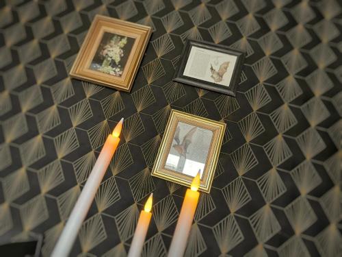 a group of three candles and framed pictures on a wall at NEW - Bat'Appart - DIJON - Insolite in Longvic