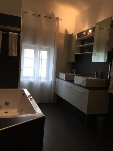 La salle de bains est pourvue de 2 lavabos, d'une baignoire et d'une fenêtre. dans l'établissement Au Lavoir, à Colombiers