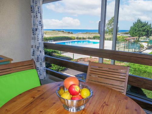 a bowl of fruit on a table with a view of a pool at Apartment Les Océanes by Interhome in Damgan