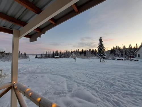 vista su un cortile coperto da neve con una casa di Aurora River Camp Glass igloos & cabins a Kiruna