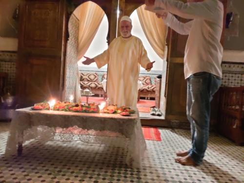Un uomo in piedi davanti a un tavolo con un prete di Riad 4 jardins a Marrakech