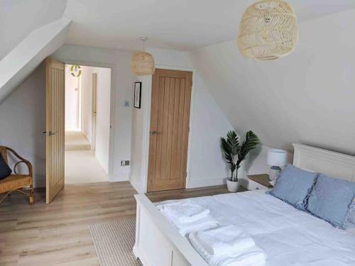 a white bedroom with a large bed with blue pillows at Seaside Cottage, 8min walk to beach. Dog friendly. in Norwich