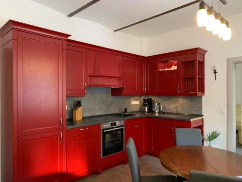 a kitchen with red cabinets and a wooden table at Pension Gesundbrunnen in Müglitztal