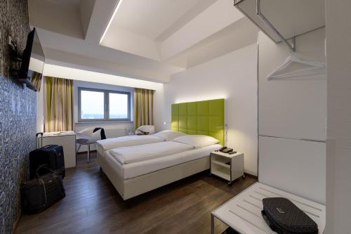ein Schlafzimmer mit einem weißen Bett und einer grünen Wand in der Unterkunft Panorama Hotel Schweinfurt in Schweinfurt