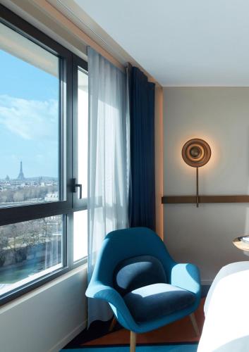 a blue chair in a room with a window at SO/ Paris Hotel in Paris