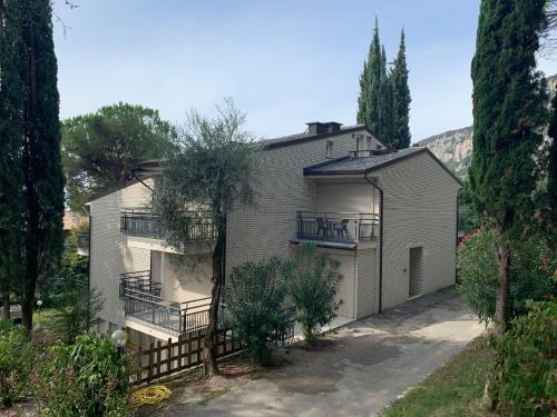 una casa grande con garaje y árboles en Apartment Parco del Garda-4 by Interhome, en Garda