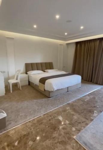 1 dormitorio con 1 cama grande y 1 silla en راحتي هوم en Al Rass