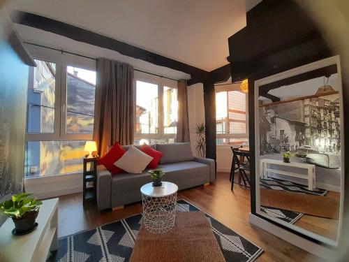 sala de estar con sofá y algunas ventanas en Andra Mari Apartamentu Turistikoak, en Bermeo