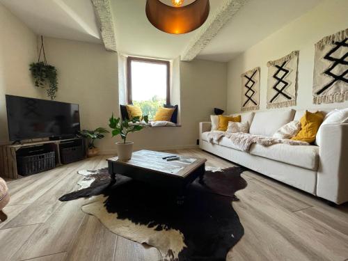 een woonkamer met een witte bank en een tafel bij L'Intemporel in La-Roche-en-Ardenne