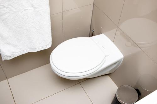 a white bathroom with a toilet and a trash can at Urban Oasis Apartments at Freedom Plaza in Windhoek